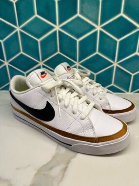 Nike White Low-Top Sneakers with Black Swoosh and Gold Trim